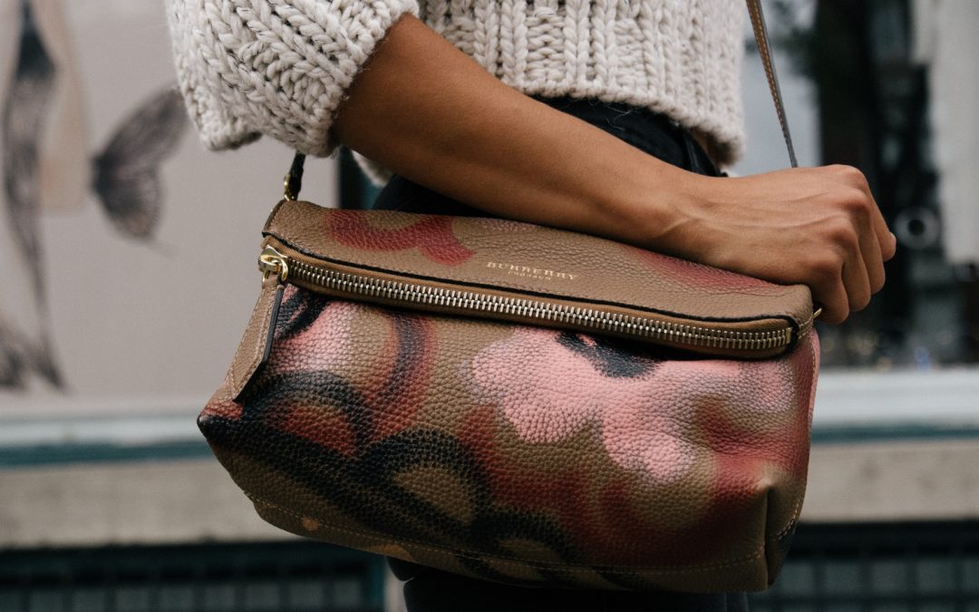 Woman holding brown and pink floral leather crossbody bag